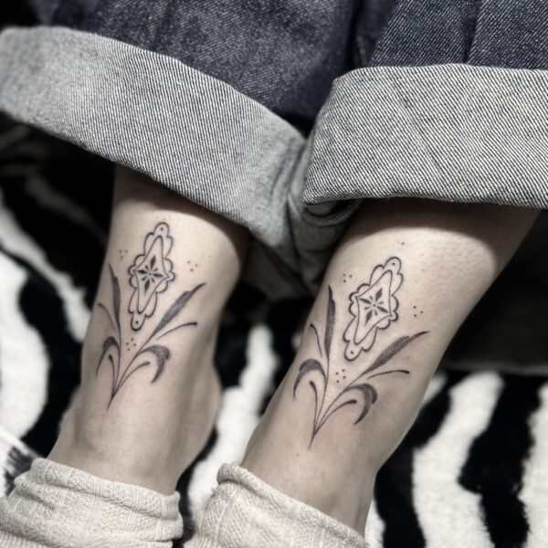 Tatouages ornementaux symétriques aux chevilles avec motifs floraux et dotwork