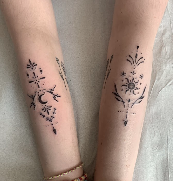 Tatouages ornementaux sur avant-bras avec soleil, lune, étoiles et motifs floraux